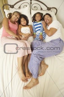Young Family Relaxing In Bedroom