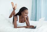 Smiling woman lying on her belly using a laptop