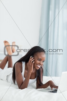 Portrait of a woman using a notebook while making a phone call