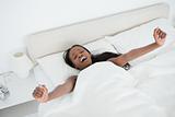 Woman yawning and stretching her arms while waking up