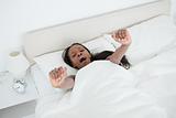 Young woman yawning and stretching her arms while waking up