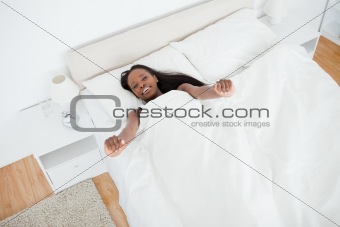 Above view of a woman stretching her arms while waking up