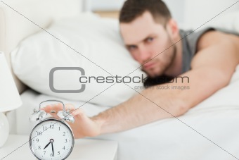 Unhappy man switching off his alarm clock