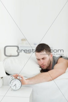 Portrait of a tired man being awakened by an alarm clock