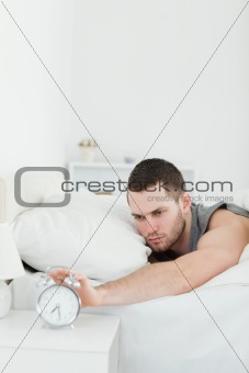 Portrait of a unhappy man being awakened by an alarm clock