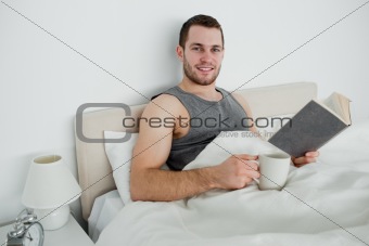 Young man reading a novel while drinking a coffee