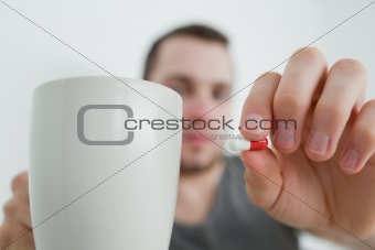 Man showing a pill and and a mug