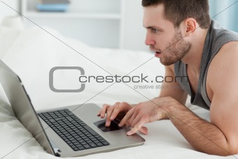 Man using a laptop while lying on his belly