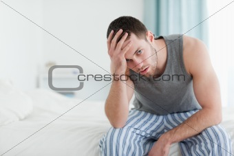 Tired man sitting on his bed