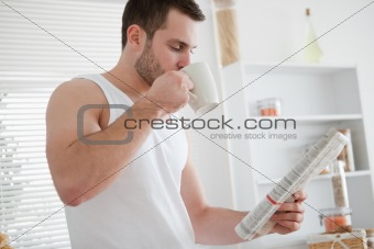 Young man drinking coffee while reading the news