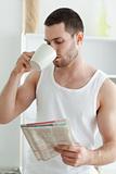 Portrait of a young man drinking tea while reading the news