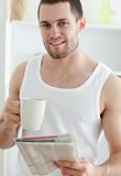 Portrait of a handsome man drinking coffee while reading the news