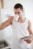 Portrait of a smiling man drinking tea while reading the news