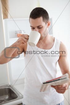 Portrait of a smiling man drinking tea while reading the news