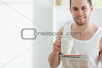 Good looking man drinking tea while reading the news