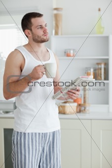 Portrait of a sports man drinking tea while reading the news