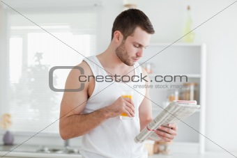 Man drinking orange juice while reading the news