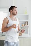 Portrait of a young man drinking orange juice while reading the news
