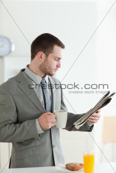 Portrait of a businessman having breakfast while reading the news