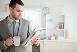 Businessman drinking coffee while reading the news
