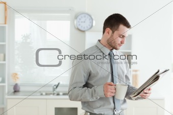 Young businessman reading the news while having breakfast