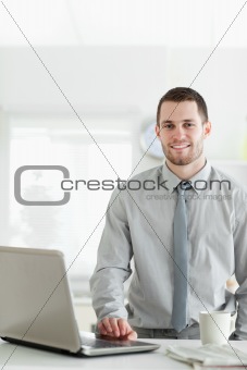 Portrait of a businessman using a laptop while drinking tea