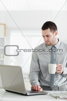 Portrait of a businessman using a notebook while drinking tea
