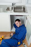 Portrait of a smiling repairman fixing a sink