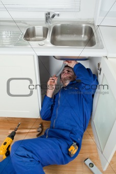 Portrait of a smiling plumber fixing a sink