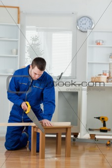 Portrait of a handsome handyman cutting a wooden board