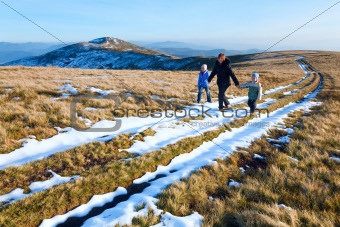 Family walk on autumn  mountain plateau with first winter snow