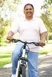Senior Man Riding Bike In Park