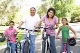Grandparents In Park With Grandchildren Riding Bikes