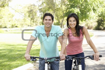 Young Couple Riding Bikes In Park