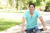 Young Man Riding Bike In Park