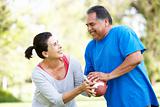 Senior Couple Exercising With American Football In Park