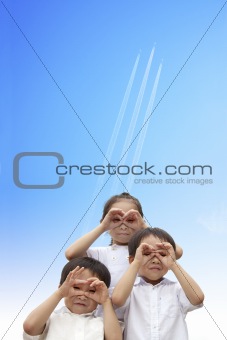 three happy kids watching the aircraft flying through to sky