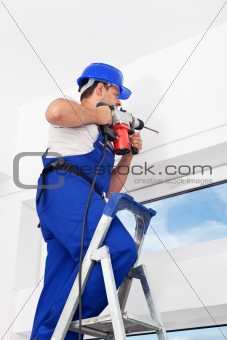 Worker drilling hole in wall