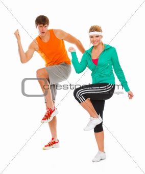 Healthy girl and guy in sportswear doing aerobics isolated on white
