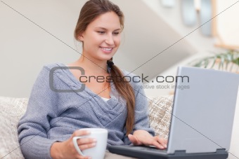 Woman using a laptop while having a tea