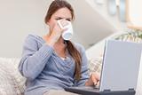 Woman using a laptop while drinking a cup of a tea