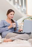 Portrait of a woman using a laptop while having a tea