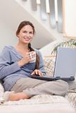 Portrait of a woman using a laptop while having a coffee