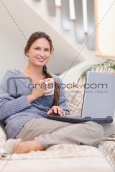 Portrait of a woman using a laptop while having a coffee