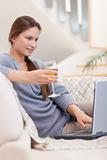 Portrait of a woman having a glass of white wine while using her laptop