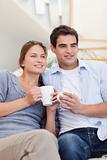 Portrait of a couple drinking coffee while watching TV