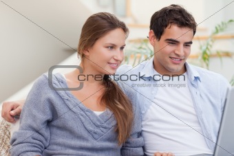 Joyful couple using a laptop