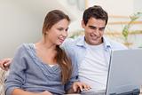 Delighted couple using a laptop