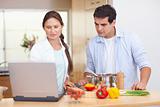 Couple using a laptop to cook