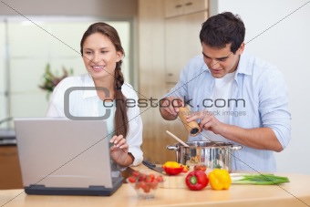 Young couple using a notebook to cook